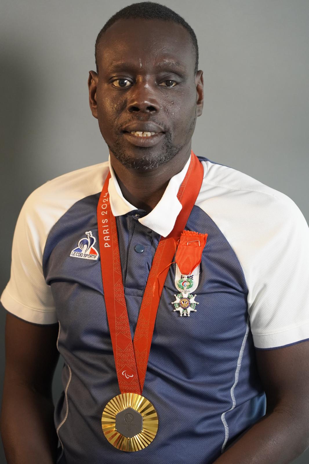 khalifa youme portant sa légion d'honneur et sa médaille d'or des Jeux Paralympiques de Paris 2024